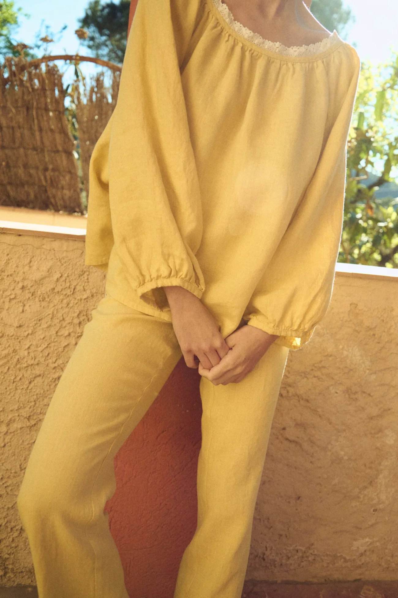 woman wearing straight fit linen drawstring pants styled with matching wide sleeved linen blouse