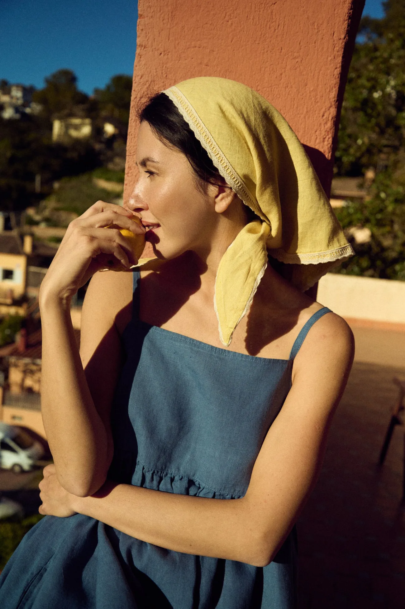 woman wearing spaghetti straps blue linen dress in midi length paired with a bandana in butter yellow