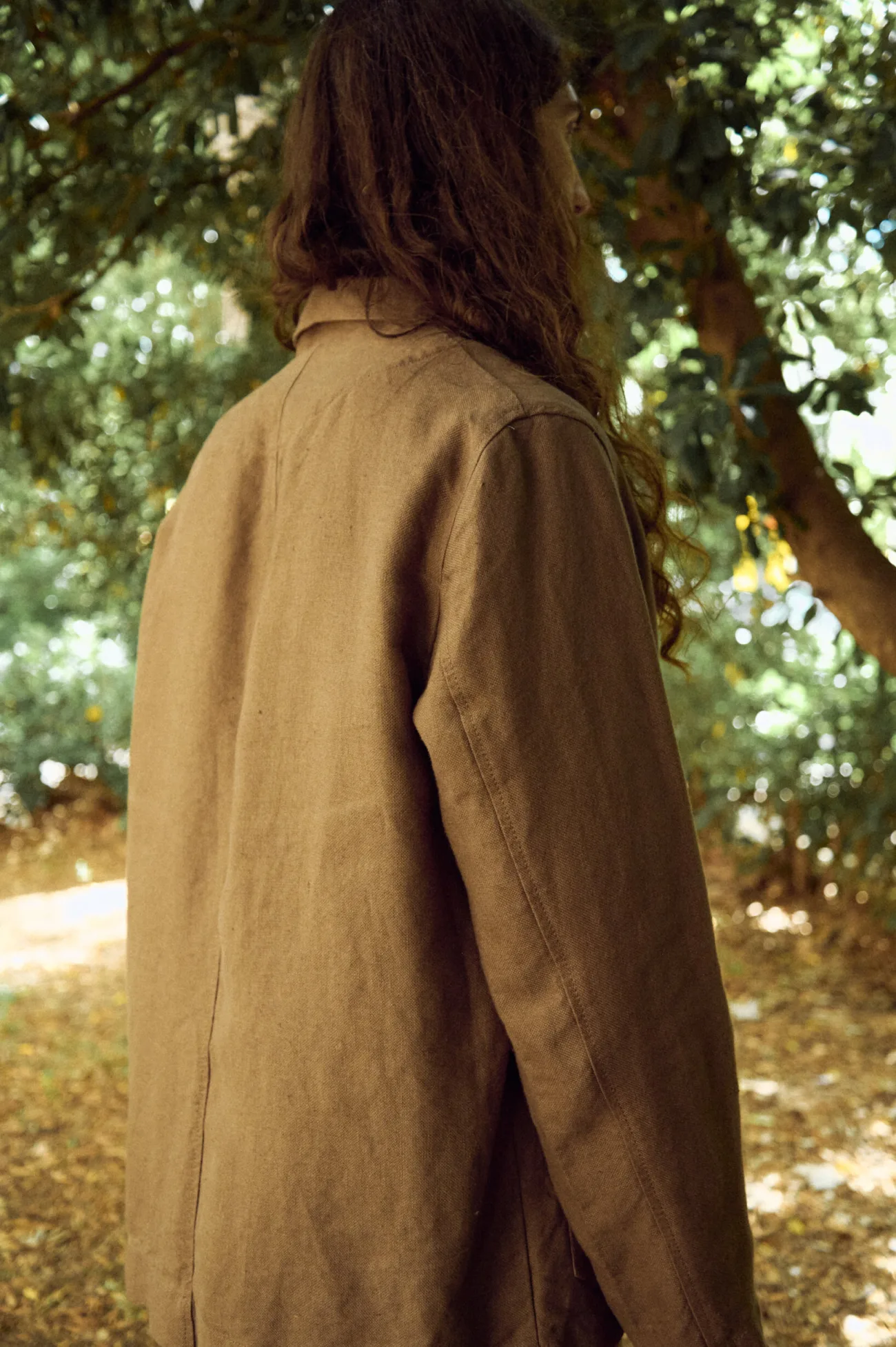 Men’s brown heavy linen jacket shown from the back, highlighting its clean straight silhouette, relaxed shoulders, long sleeves and naturally textured heavyweight linen
