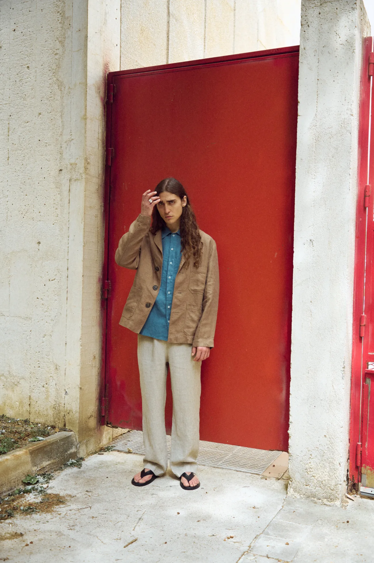 Men’s brown heavy linen jacket with an easy, structured silhouette, classic notched lapels, three-button closure and generous patch pockets, styled with a stellar blue linen shirt and relaxed natural grey linen trousers