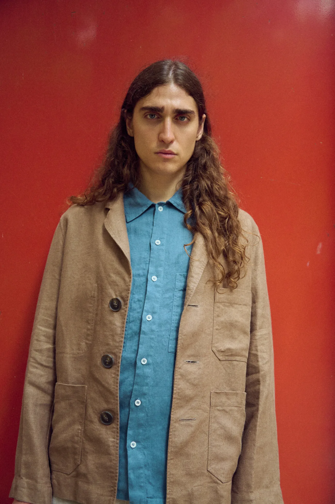 Men’s brown heavy linen jacket with a relaxed, straight silhouette, classic lapel collar, large patch pockets and oversized dark buttons, layered over a stellar blue linen shirt