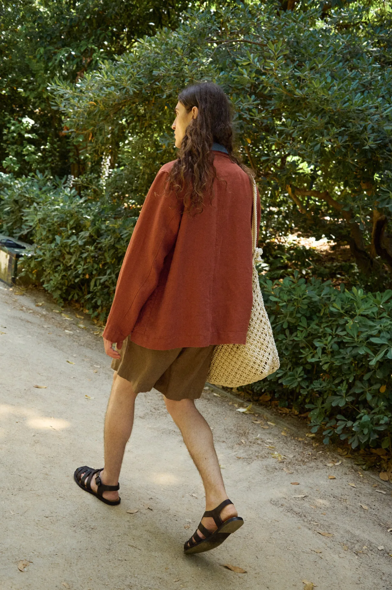 Men’s terracotta heavy linen jacket shown from the back, with a relaxed straight silhouette and clean center back seam, styled with cacao brown linen shorts