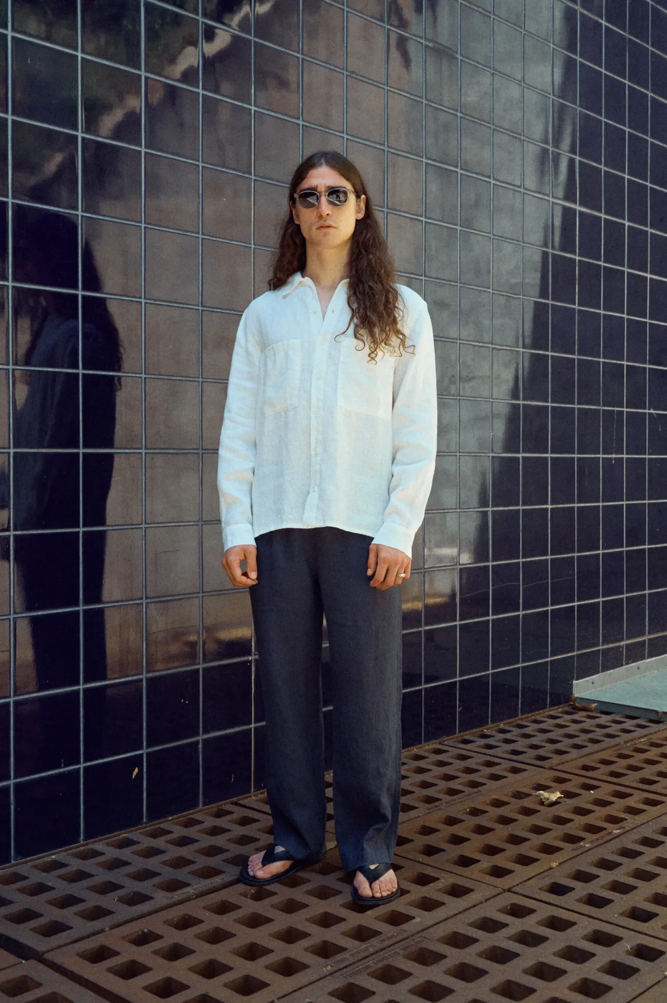 Men's graphite grey linen trousers with an easy straight-leg silhouette, worn with a relaxed white linen shirt