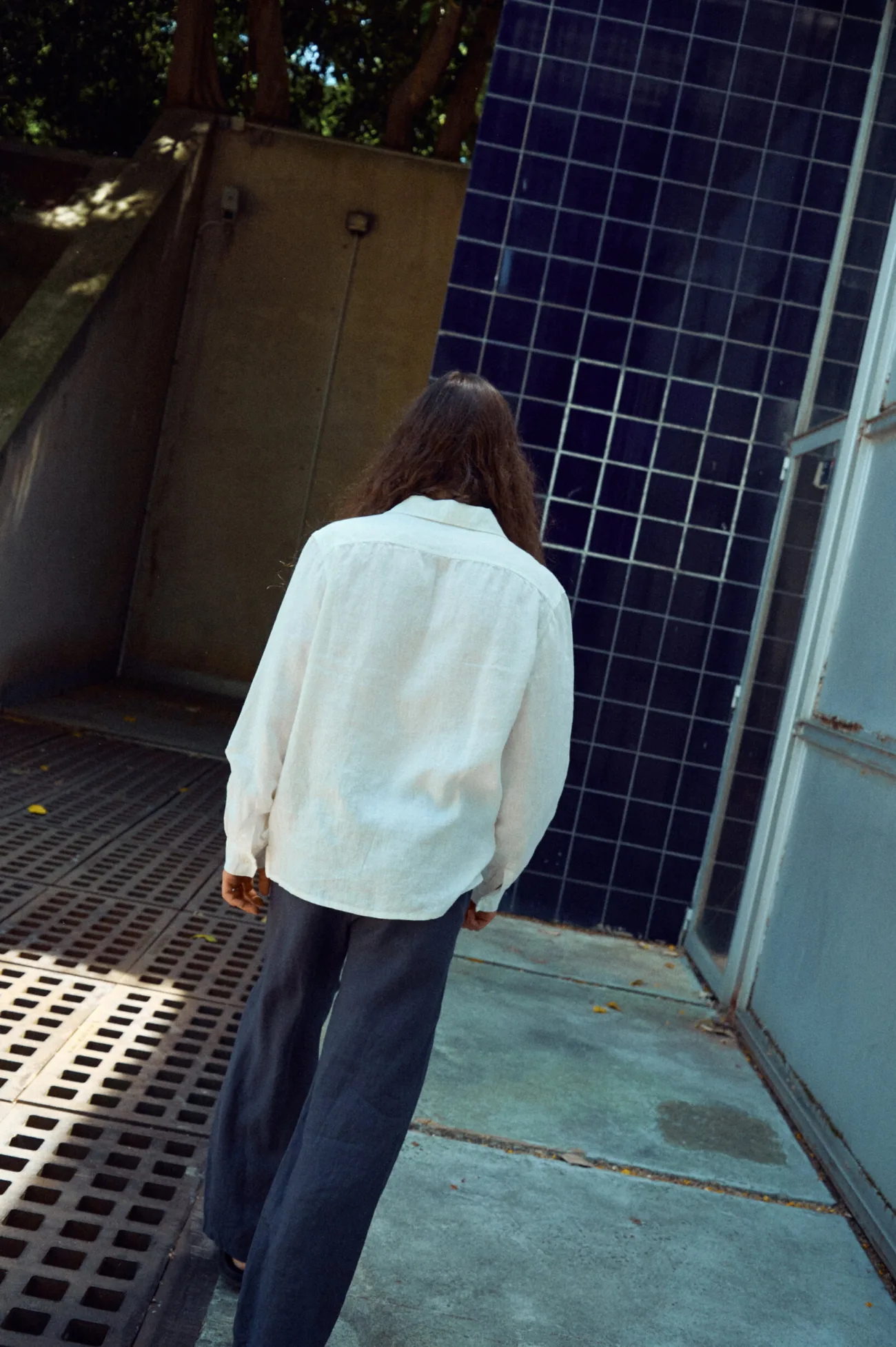Graphite grey men’s linen trousers with a relaxed wide-leg silhouette, shown from the back