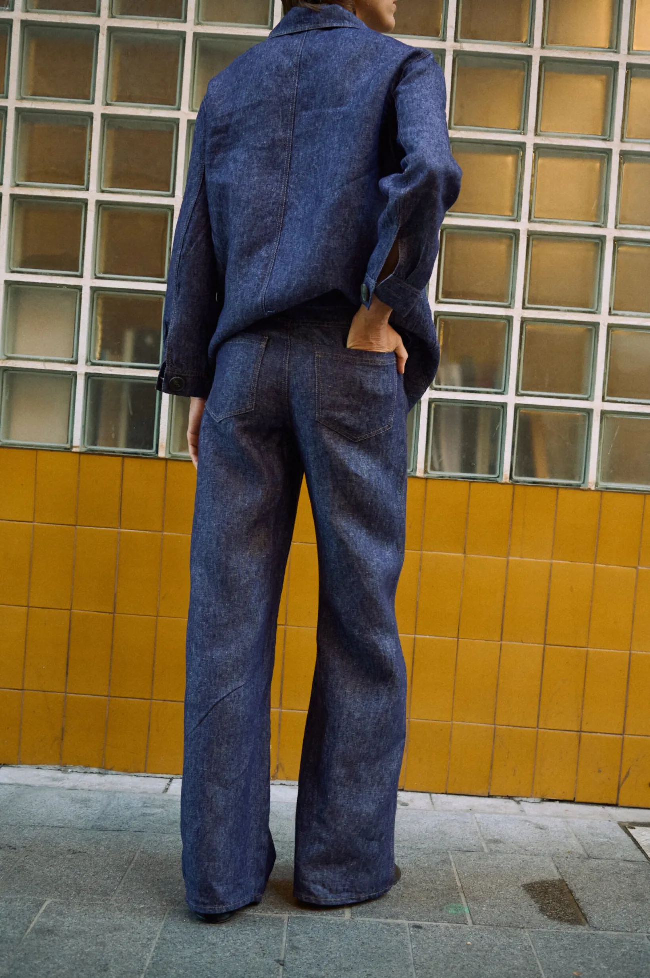 Back view of blue denim linen jeans with wide legs and two back patch pockets, paired with a matching linen jacket