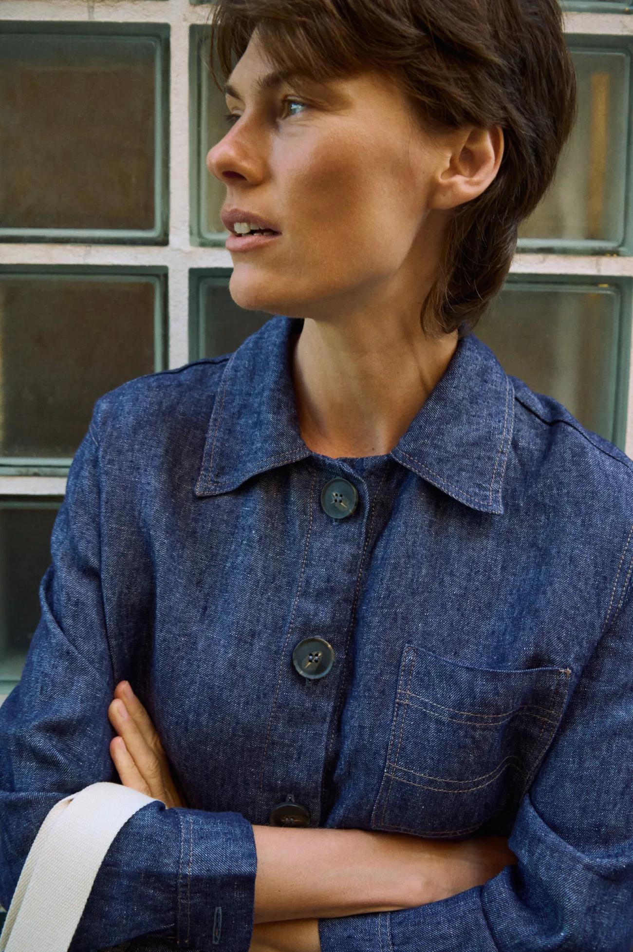 Close-up of blue denim linen jacket with button front, chest pocket, and contrast stitching