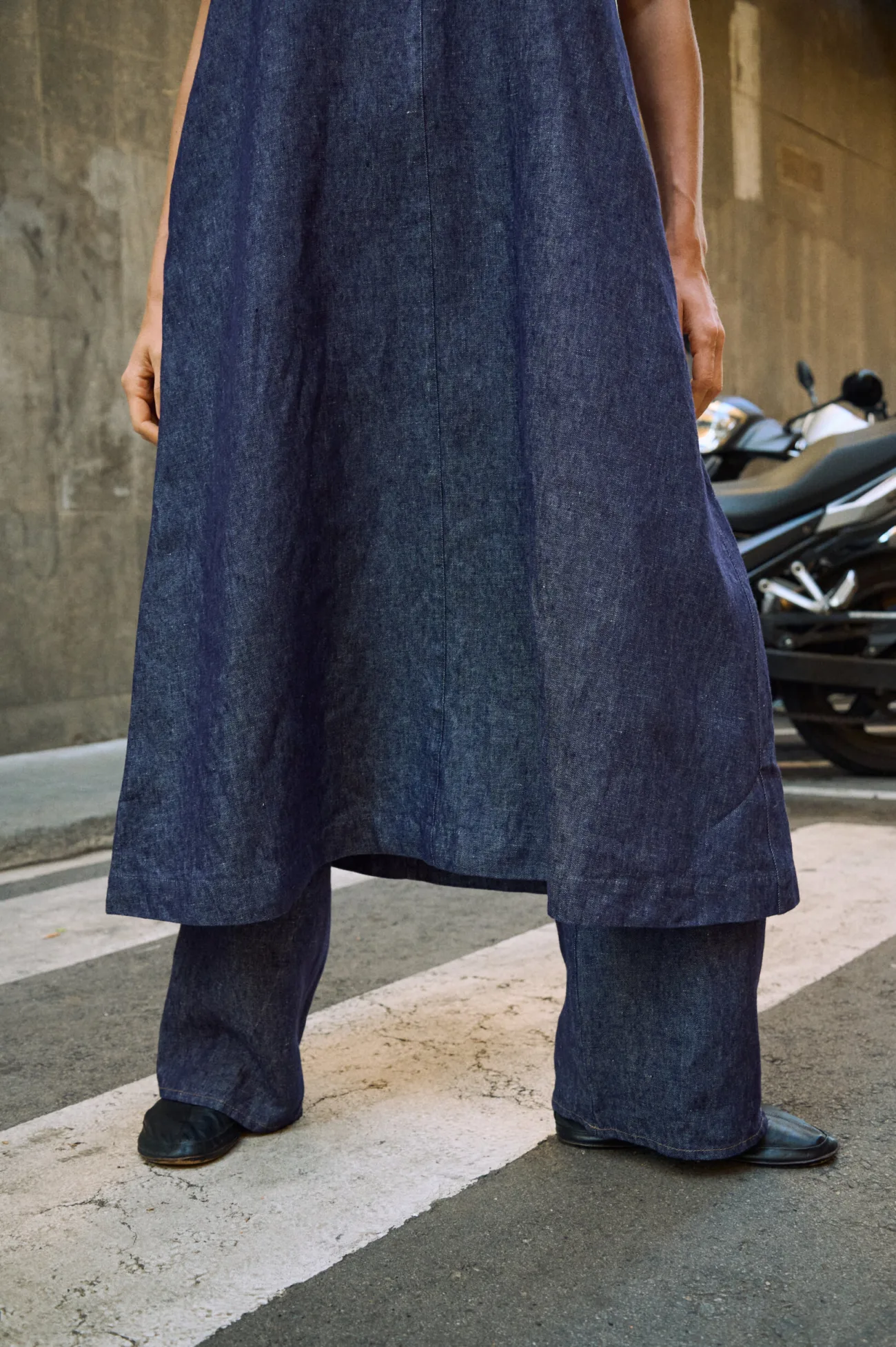 Close-up of a blue denim linen sleeveless maxi dress layered over matching wide-leg linen pants, highlighting the natural linen texture and flowing hem
