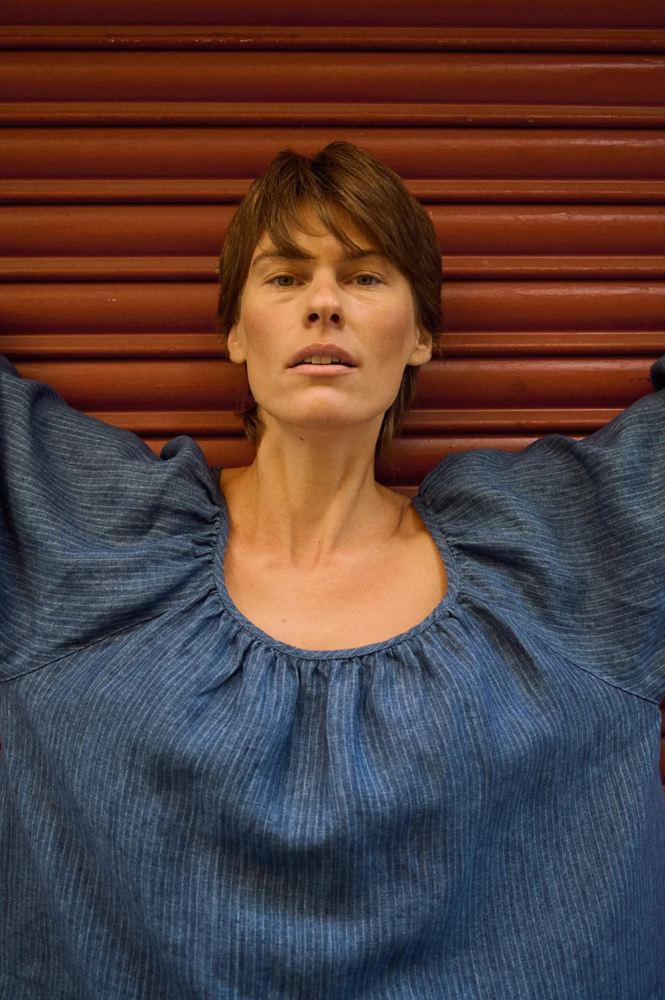 Close-up of a blue striped linen blouse highlighting the gathered scoop neckline and voluminous sleeves