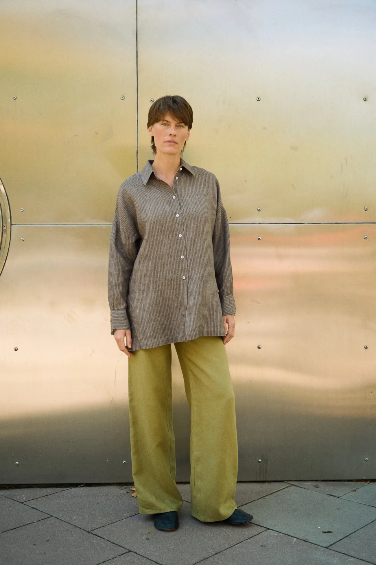 Brown striped linen button-up shirt with an oversized silhouette, styled with wide-leg olive green linen trousers
