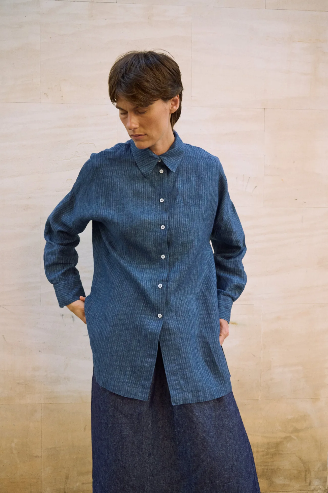 Blue striped linen button-up shirt with a long relaxed silhouette, pointed collar and buttoned cuffs