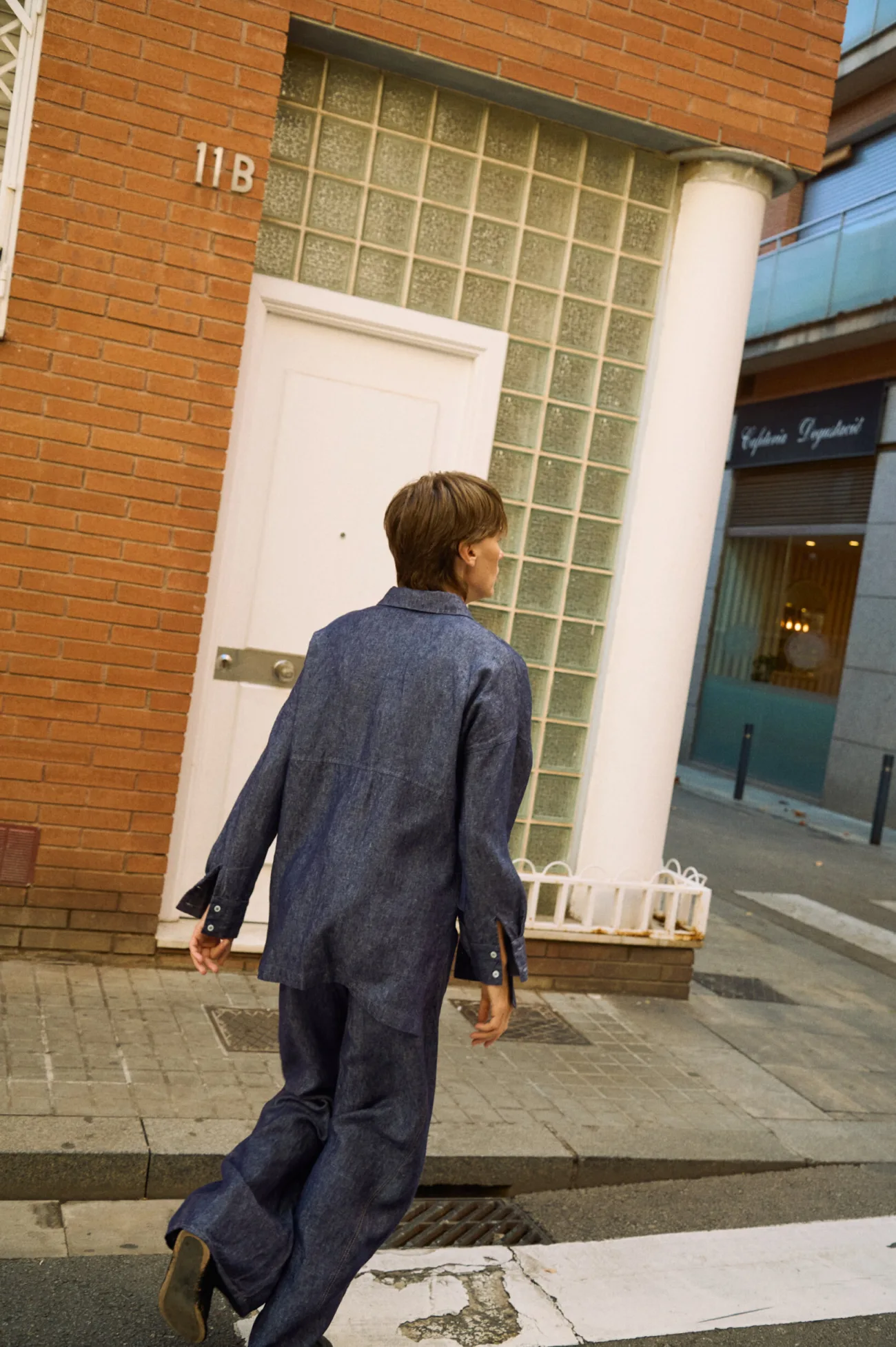 Back view of blue denim linen pants with wide legs, styled with a matching linen shirt while walking outdoors