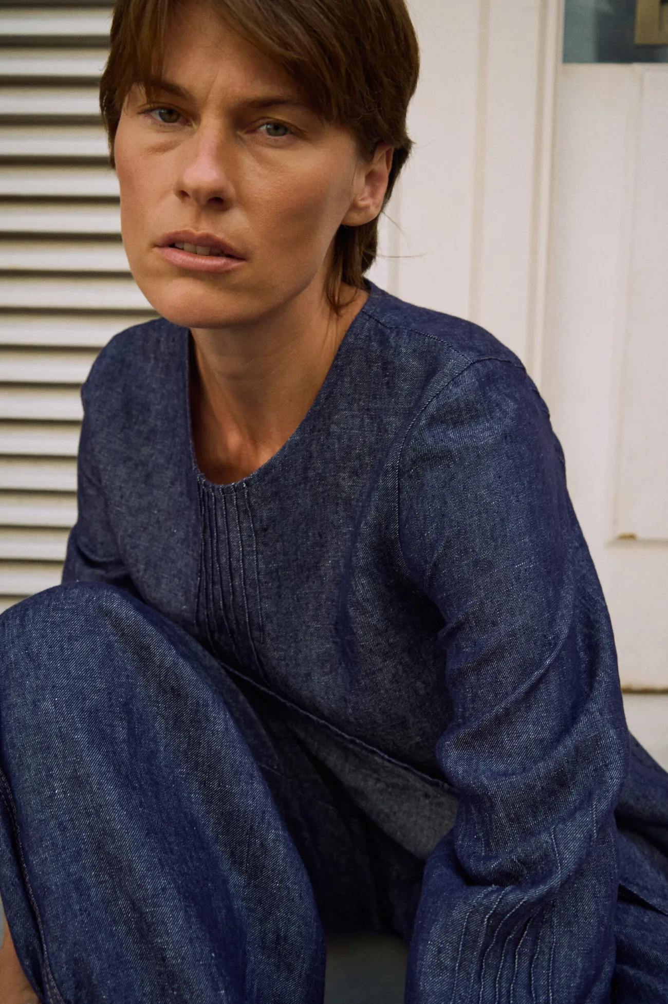 Close-up of a denim linen tunic dress highlighting the pintuck neckline detail and textured linen fabric