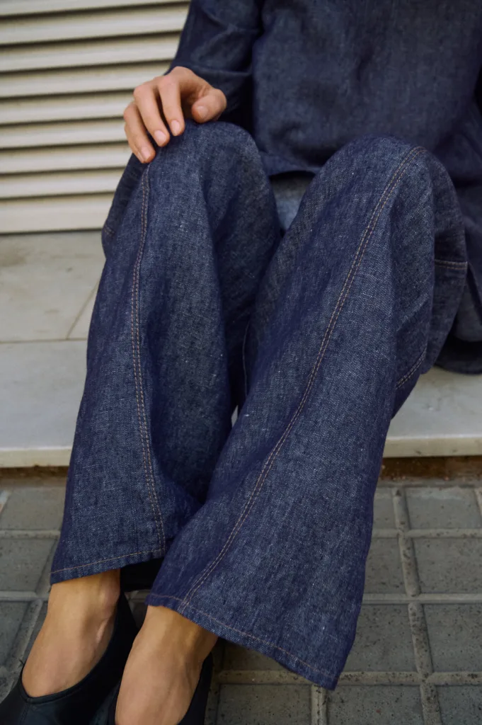 Detail view of blue denim linen pants with wide legs and contrast stitching along the front seams
